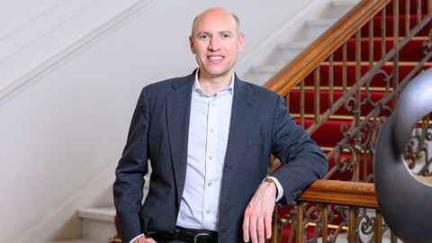 Ein Mann in einem blauen Anzug lehnt an einer Treppe