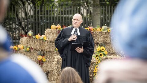 Ein Pfarrer im Talar spricht zu den Gästen