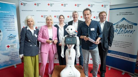 Gruppenbild mit sechs Personen und in der Mitte mit dem weißen Roboter Pepper