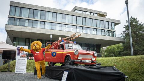 Das Maskottchen, der Hessen-Löwe steht neben dem feuerroten Trabant-Löschfahrzeug