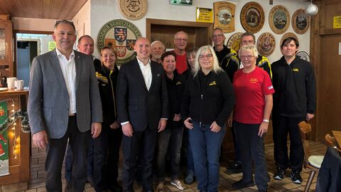 Mehrere Personen stehen in einem Schützenhaus und lachen in die Kamera.