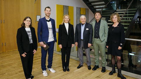 Sechs Teilnehmer der Lesung stehen lächelnd vor dem Veranstaltungsraum nebeneinander 