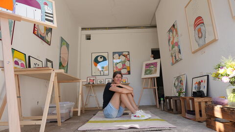 Kunst in Licher Scheunen Eine Frau sitzt inmitten von Gemälden