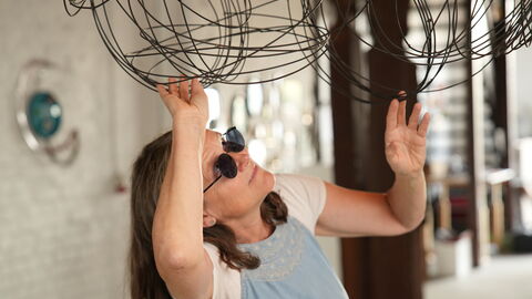 Kunst in Licher Scheunen Eine Frau schaut sich ein Kunstwerk genauer an