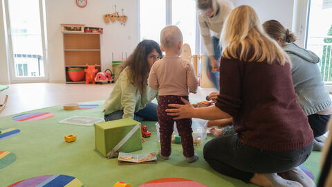 „Soziale Anlauf- und Begegnungsstätte für alle Generationen – DAS INNOVATIVE SOZIALZENTRUM“ Ein Kleinkind spielt mit mehreren Frauen