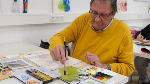 „Soziale Anlauf- und Begegnungsstätte für alle Generationen – DAS INNOVATIVE SOZIALZENTRUM“ Ein Mann malt ein Bild mit Wasserfarbe