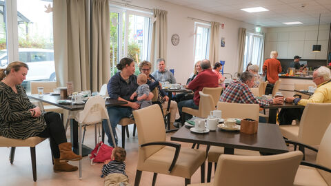 „Soziale Anlauf- und Begegnungsstätte für alle Generationen – DAS INNOVATIVE SOZIALZENTRUM“ Personen aus unterschiedlichen Generationen sitzen zusammen an Tischen