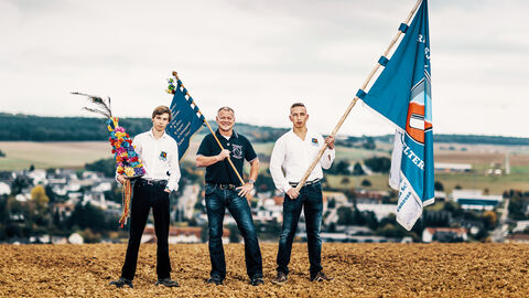 Drei Männer posieren mit Fahnen