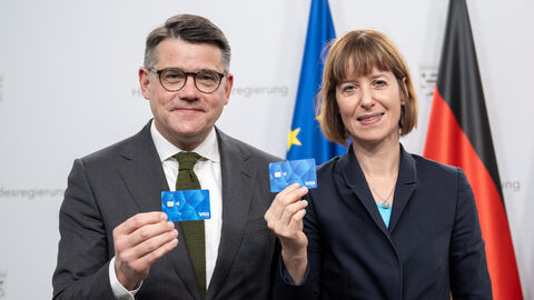 Ministerpräsident Boris Rhein und Sozialministerin Heike Hofmann stehen nebeneinander und halten jeweils eine blaue Geldkarte hoch.