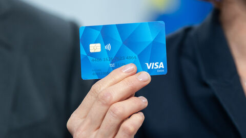 Eine Hand hält eine blaue Geldkarte hoch.