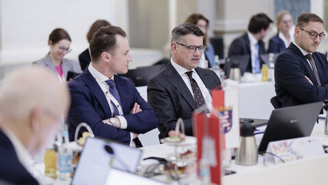 Ministerpräsidentenkonferenz Berlin 2025 Zwei Männer sitzen in Anzügen nebeneinander. Der rechte schaut nach vorne, während der linke den anderen ansieht.