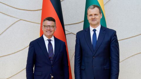 Ministerpräsident Boris Rhein trifft in Vilnius den litauischen Regierungschef Gintautas Paluckas. Zwei Männer stehen vor der deutschen und litauischen Landesflagge nebeneinander.