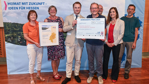 Eine Gruppe steht bei der Preisverleihung mit ihrem Preis zusammen.