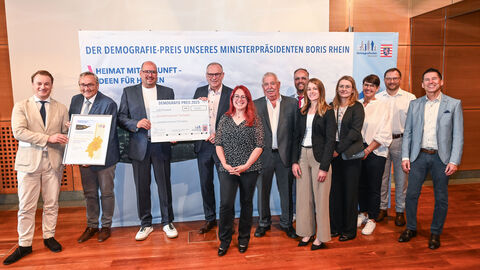 Eine Gruppe steht bei der Preisverleihung mit ihrem Preis zusammen.