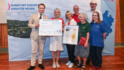 Eine Gruppe steht bei der Preisverleihung mit ihrem Preis zusammen.