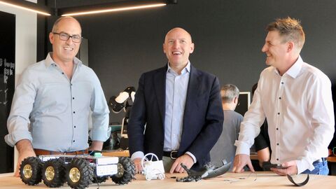 Minister Pentz besucht Projekt makeIT Minister Pentz steht gemeinsam mit zwei weiteren Personen an einem Tisch auf dem einzelne elektrische Bauteile liegen.