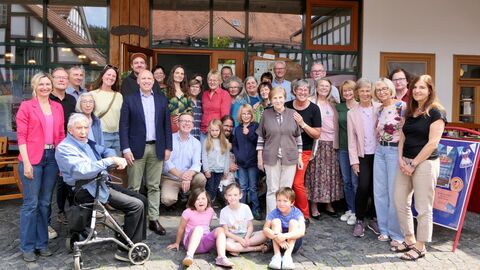 Gruppenbild mit Minister Manfred Pentz, den Organisatoren des Dorfladens und vielen Gästen und Untersützern Über 20 Menschen von jung bis alt stehen vor einem Geschäft.