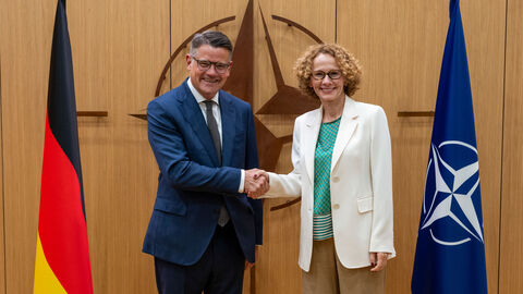 Ministerpräsident Boris Rhein (links), der neben der Flagge der Bundesrepublik Deutschland steht, schüttelt NATO-Generalsekretärin Radmila Šekerinska (rechts), die neben der Flagge der NATO steht, die Hand.