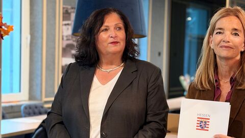 Zwei Frauen stehen nebeneinander - eine hält einen Förderbescheid in den Händen.