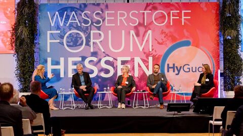 Fünf Personen sitzen im Rahmen der Podiumsdiskussion zum Thema „Hype und Wirklichkeit“ auf einer Bühne