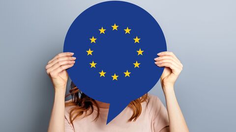 Frau hält sich eine Sprechblase im Europadesign vor das Gesicht