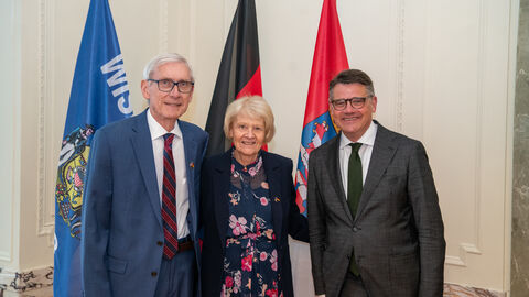 Gruppenfoto von Gouverneur Tony Evers, seiner Frau Kathy und Ministerpräsident Boris Rhein vor den Flaggen Wisconsins, Hessens und Deutschlands