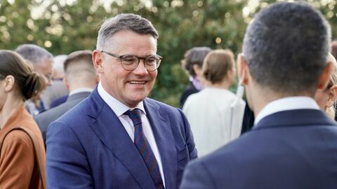 Ministerpräsident Boris Rhein steht vor einem Mann und lächelt ihn an.