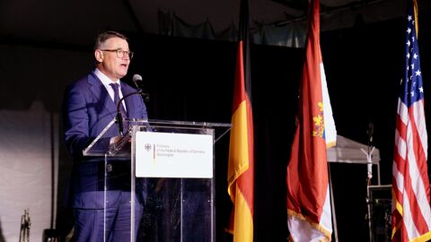 Ministerpräsident Rhein steht auf der Bühne und spricht in ein Mikofron