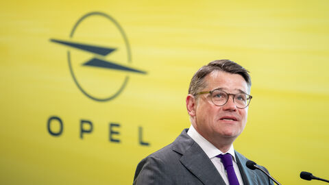 Ministerpräsident Rhein vor dem Logo von Opel