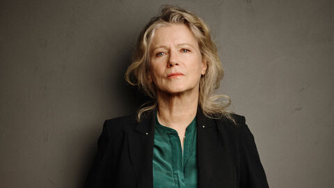 Eine Frau steht vor einer grauen Wand