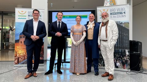 Eine Gruppe Personen steht zusammen vor Aufstellern des Hessentags in Bad Vilbel.