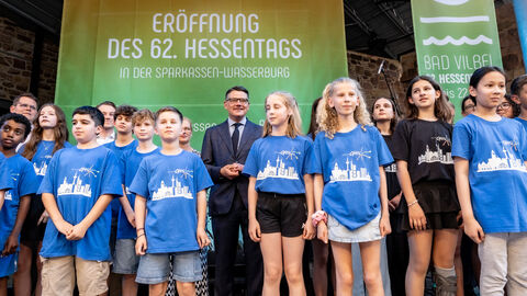 Eine Gruppe Kinder steht mit Ministerpräsident Boris Rhein auf einer Bühne