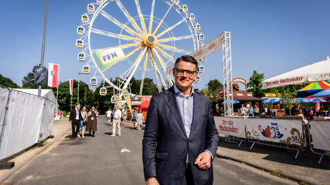 Ministerpräsident Boris Rhein steht vor einem Riesenrad. 