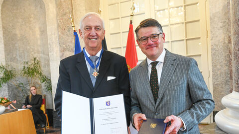 Zwei Männer stehen nebeneinander und halten eine Urkunde hoch.